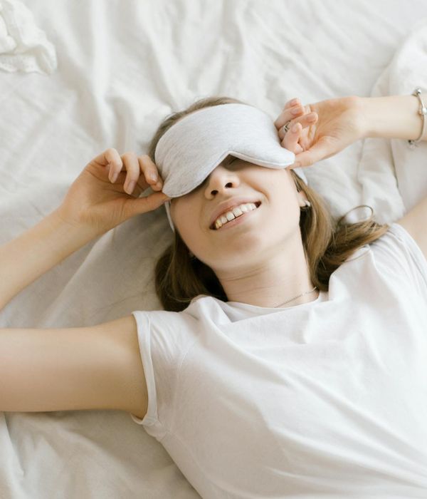 Woman smiling peacefully in a room with soft light.